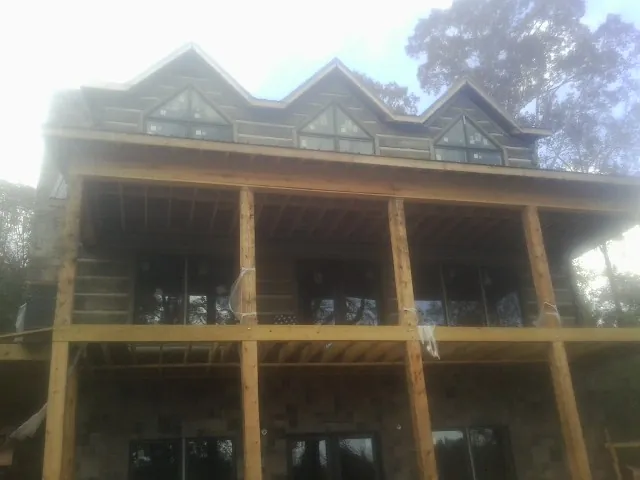 Dormers and porch framing on a large log home under construction — Roof Coating work by our crew in Lowell